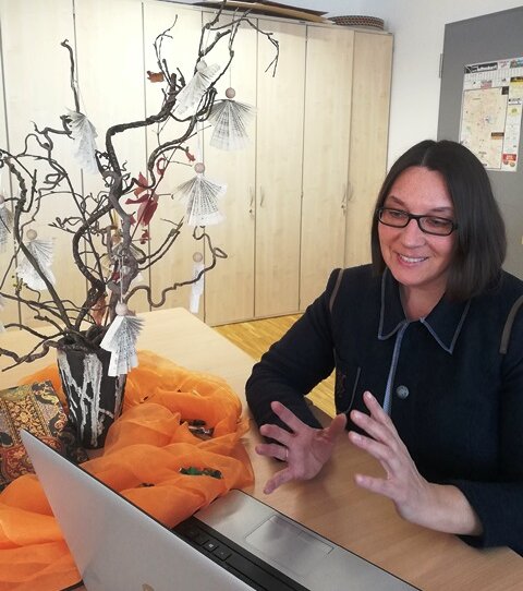 Eine Frau sitz vor einem PC-Bildschirm und spricht über Videochat mit einem Ehrenamtlichen