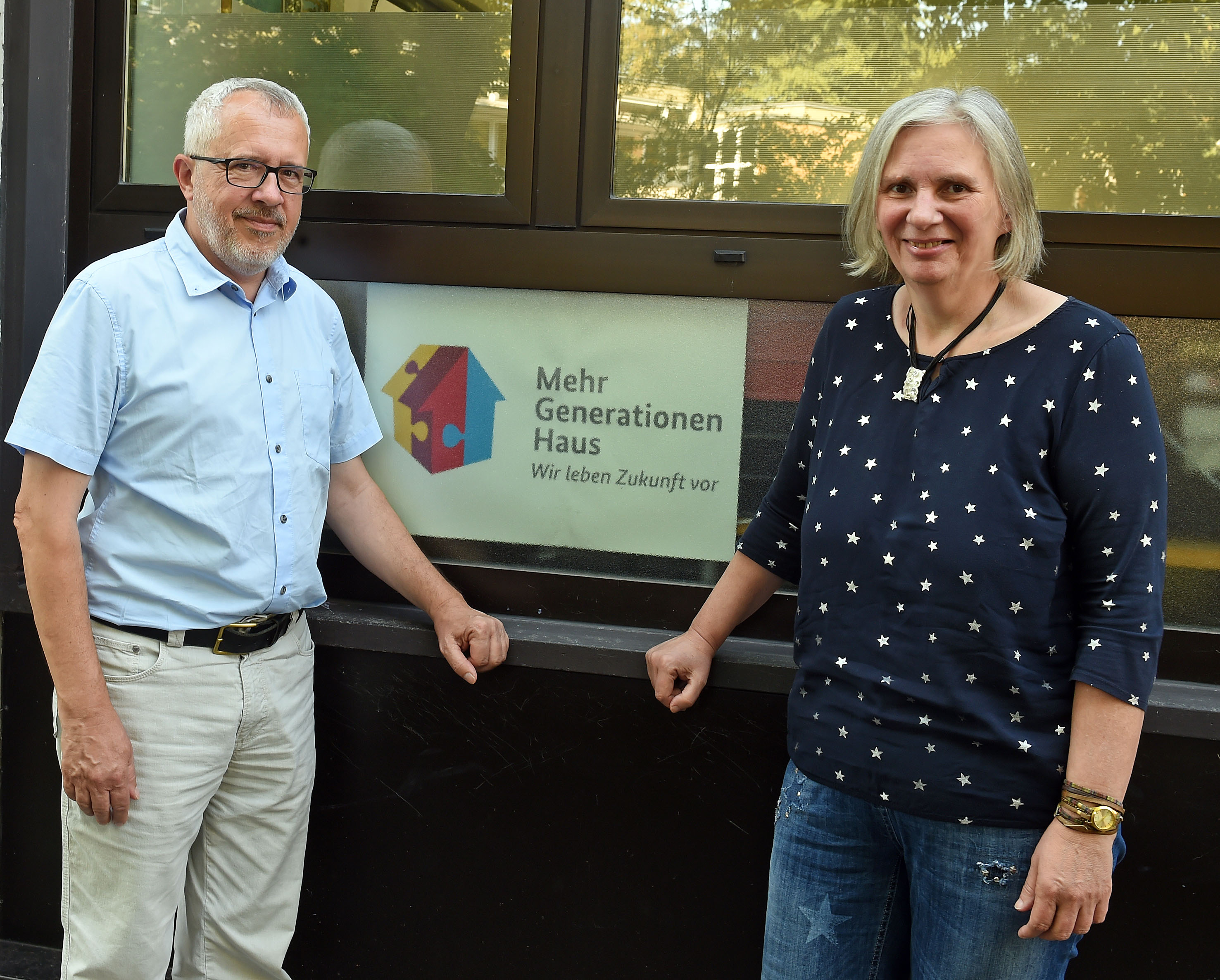 Der Amtsinahber und seine Nachfolgerin stehen vor dem Schild Mehrgenerationenhaus